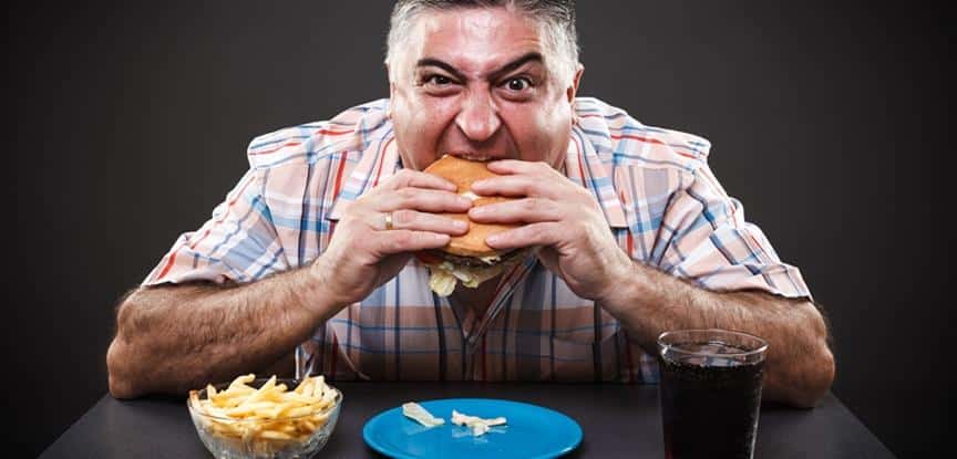 homem comendo hambúrguer, batata e tomando refrigerante