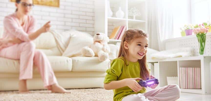 criança jogando no videogame e mãe atras brigando