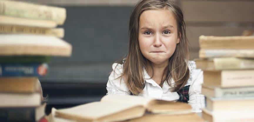 foto de menina com cara de choro ao lado de livros