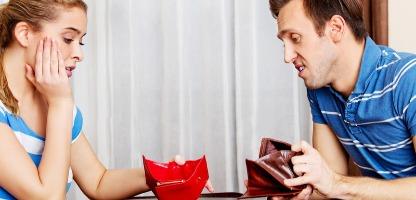Casal com conta conjunta preocupado sentado à mesa com carteiras vazias